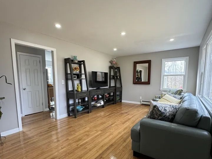 Second view of the open living area with hardwood flooring and recessed lighting