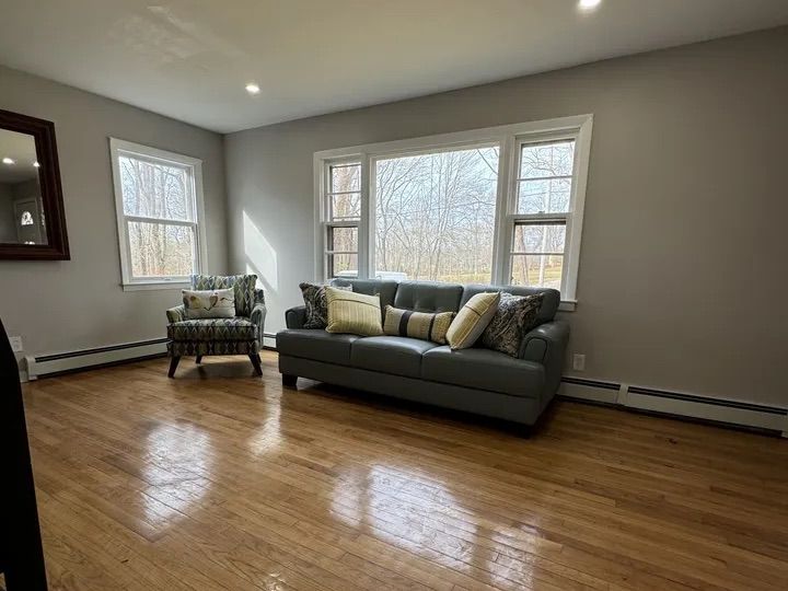 Living room with refinished hardwood floors and large windows in the Lebanon, CT Cape