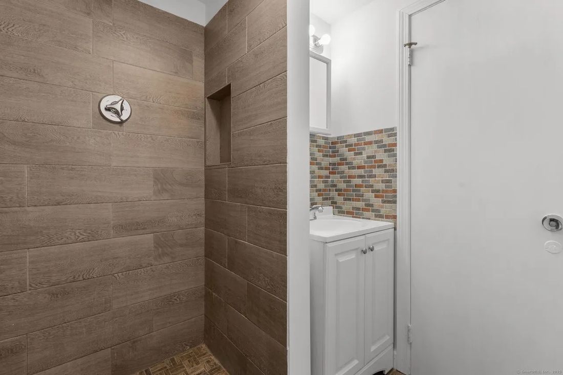 Tiled walk-in shower and mosaic-tile vanity backsplash in a renovated New Britain apartment