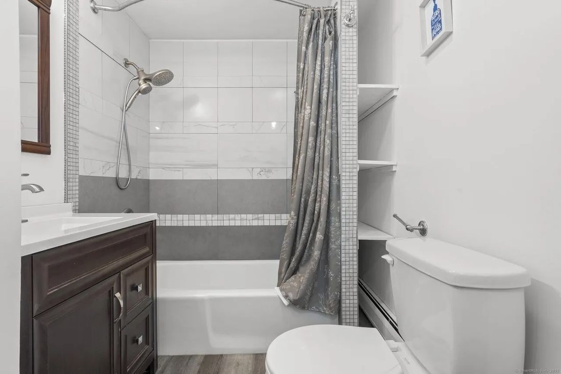 Full bathroom with tub-shower, tile surround and new vanity in the New Britain triplex