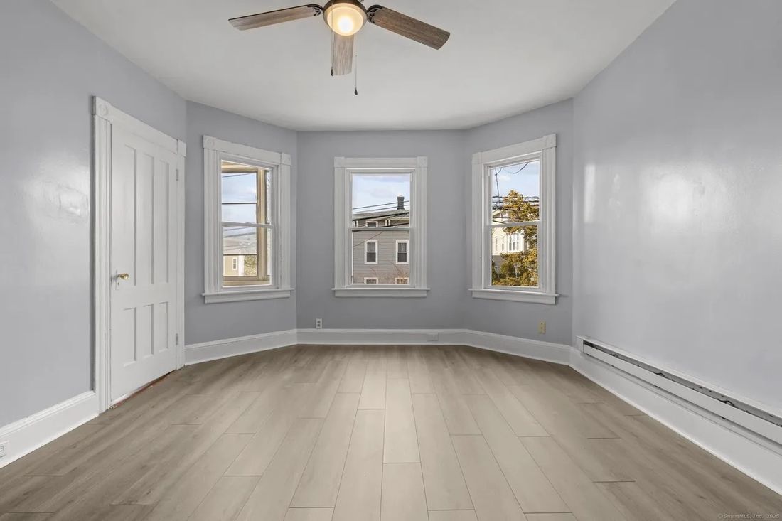 Bedroom with curved bay window and fresh paint in the New Britain multi-family