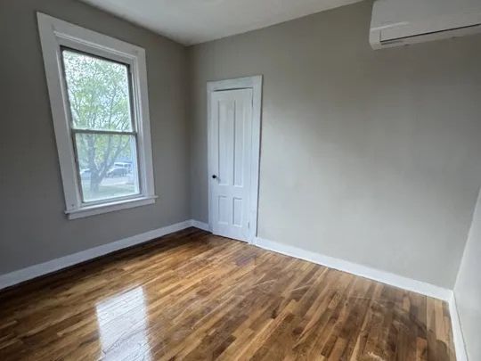 Bedroom with restored hardwood and a newly installed ductless mini-split head in Norwich, Connecticut