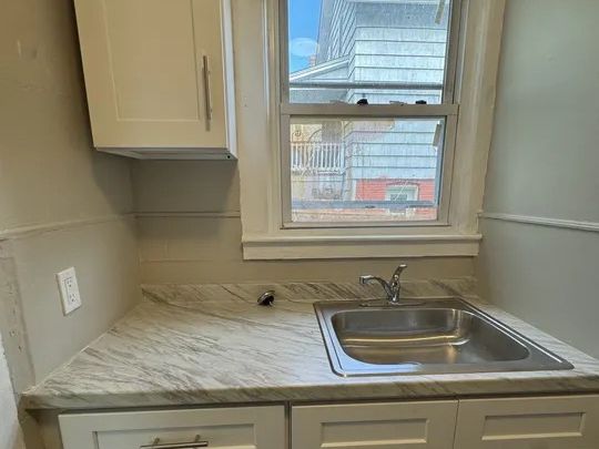 First-unit kitchen with new white cabinets and counters in the Norwich two-family