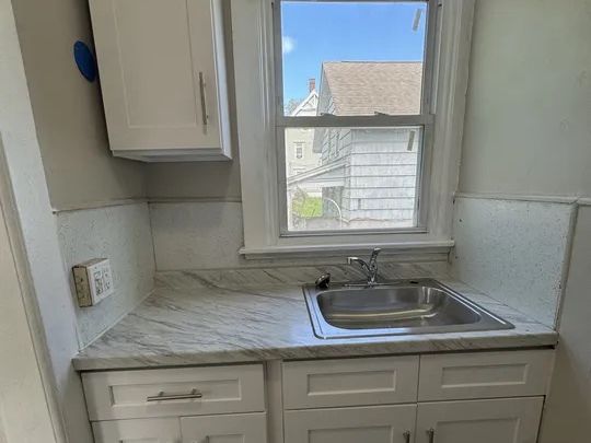 Second-unit kitchen with white cabinetry and updated sink in Norwich, CT