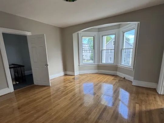 Living room with refinished hardwood floors and bay window in the Norwich, CT two-family
